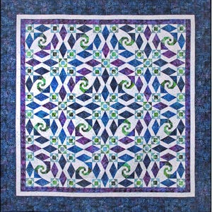 May include: A square quilt featuring a geometric pattern of blue, purple, and green diamond shapes on a white background. The design includes swirling spiral motifs and small square accents, all enclosed within a dark blue mottled fabric border.