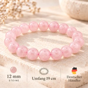 Könnte beinhalten: Ein kreisförmiges Armband aus glatten, polierten hellrosa Perlen. Der Text auf dem Bild gibt an, dass die Steine 12 mm groß sind und das Armband einen Umfang von 19 cm hat. Die Perlen haben ein einheitliches, halbtransparentes Erscheinungsbild.