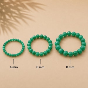Könnte beinhalten: Drei kreisförmige Armbänder aus glatten, polierten grünen Perlen. Die Armbänder sind nach Größe angeordnet, wobei Beschriftungen die Perlendurchmesser von 4 mm, 6 mm und 8 mm angeben. Jedes Armband besteht aus einer fortlaufenden Reihe grüner Kugeln.