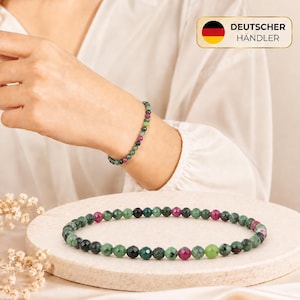 Könnte beinhalten: Ein Perlenarmband mit kleinen, facettierten, runden Steinen in den Farben Dunkelgrün, Waldgrün und leuchtendem Magenta. Das Armband besteht aus einzelnen polierten Perlen, die in einem sich wiederholenden Muster aus Grün und Pink aufgereiht sind.