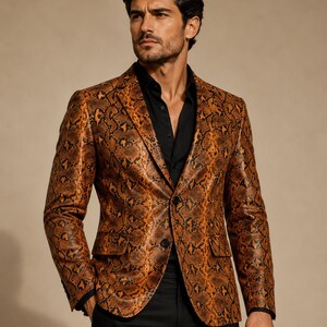 Peut inclure: Un blazer avec un motif peau de serpent orange et noir vif, doté d'un revers cranté, de deux boutons sur le devant et de deux poches à rabat. Le vêtement est porté sur une chemise boutonnée noire unie et un pantalon noir.