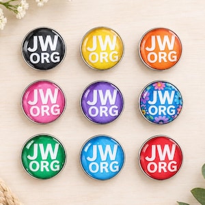 May include: A set of nine circular pins with a metallic silver rim. Each pin features the white text JW.ORG. The pins are colored black, yellow, orange, pink, purple, blue with a floral pattern, green, light blue, and red.