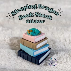 May include: A clicker featuring a stack of four books in pink, tan, light blue, and dark blue, topped with a small teal dragon with gold accents. The text "Sleeping Dragon Book Stack Clicker" is displayed above the object in a curved font.