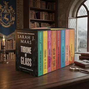 Op de afbeelding: Een boekenboxset getiteld Throne of Glass: The Complete Collection door Sarah J. Maas. De zwarte doos bevat gouden tekst, terwijl de acht kleurrijke boekruggen titels tonen zoals The Assassin's Blade, Crown of Midnight en Kingdom of Ash.