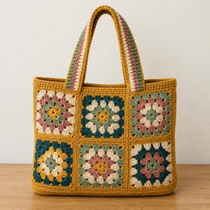 May include: A mustard yellow crochet tote bag featuring six square granny square motifs in shades of teal, dusty rose, cream, and yellow. The bag has two matching crochet handles with striped detailing in green, cream, and dusty rose colors.