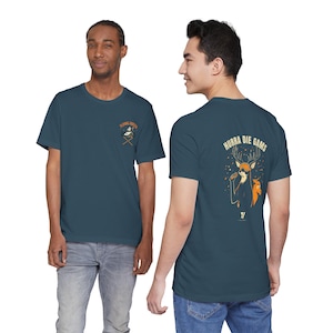 May include: A dark blue short-sleeve t-shirt featuring a small graphic on the front chest with a house and crossed tools. The back displays a large illustration of a deer holding a microphone with the text HURRA DIE GAMS above it.