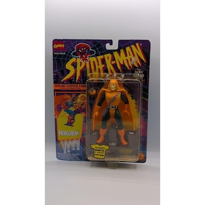 May include: A Marvel Comics Spider-Man action figure of the Hobgoblin in original packaging. The figure wears an orange hood and cape with a black and orange suit. The card features the text Spider-Man, Hobgoblin, and Exclusive Marvel T-Shirt Offer Inside.