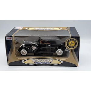 May include: A black die-cast metal model car in a rectangular box. The box features the text Collector's Quality Model and a gold circular seal stating 1st Choice Metal Die-Cast with Plastic Parts. The car has white-walled tires and chrome wheels.