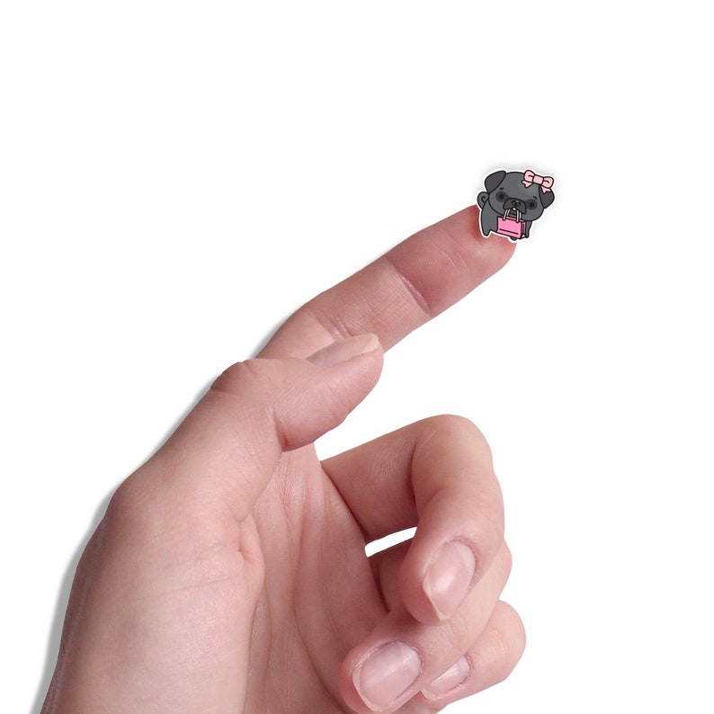 May include: A finger pointing upwards with a small black and white pug sticker with a pink bow and a pink shopping bag on it.