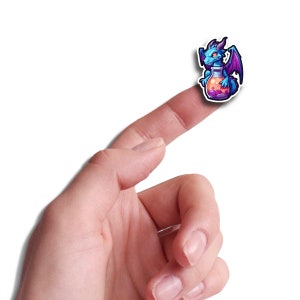 May include: A blue and purple dragon sticker holding a potion bottle. The sticker is on a finger.