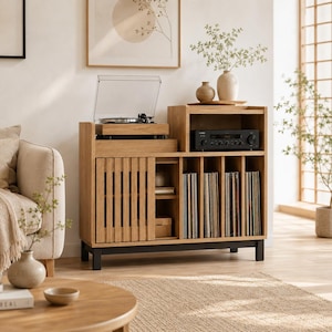 Puede incluir: Un mueble multimedia de madera de roble claro con una superficie superior para un tocadiscos, un estante abierto para un receptor de audio, una puerta corredera de listones y compartimentos verticales para discos de vinilo sobre una base de metal negro.
