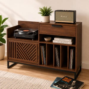 Peut inclure: Un meuble multimédia en bois foncé avec un cadre en métal noir, comprenant une platine vinyle à gauche, un tiroir, des étagères ouvertes et des séparateurs verticaux pour disques. Une enceinte Marshall, une plante et des livres sont posés dessus.