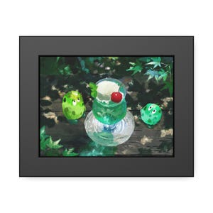 May include: A framed digital illustration featuring a glass of green melon soda topped with a scoop of white ice cream and a bright red cherry. Two small, round, green creatures with white eyes flank the glass, set against a dark leafy background.