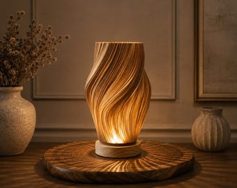 Pode incluir: Um candeeiro de mesa com um abajur cilíndrico torcido, de cor clara e nervuras verticais, que emite um brilho quente. O candeeiro assenta numa base circular de madeira, sobre uma plataforma redonda de madeira que reflete a luz em padrão radial.