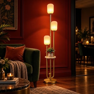 May include: A floor lamp with a gold-toned metal frame featuring three vertical poles of varying heights, each topped with a ribbed white glass shade. A circular white marble shelf is positioned in the center, holding a small potted green plant.