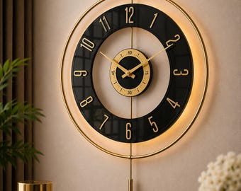 May include: A circular wall clock featuring a black ring with gold numerals from 1 to 12, a central gold dial with a 60-second track, gold hands, and a gold pendulum. The clock is framed by a thin gold ring with integrated warm LED lighting.