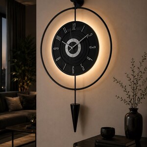 May include: A circular black wall clock featuring a central dial with white numerals from 1 to 12, surrounded by a thin black metal ring frame. The clock includes a downward-pointing black pendulum and emits a warm glow from behind the dial.