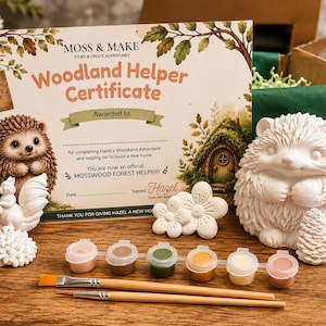 Może przedstawiać: Zestaw kreatywny zawierający certyfikat Woodland Helper, białą ceramiczną figurkę jeża, białą figurkę wiewi&oacute;rki, dwa białe kształty kwiat&oacute;w, sześć małych pojemnik&oacute;w z farbą w r&oacute;żnych kolorach oraz dwa drewniane pędzle do projekt&oacute;w.