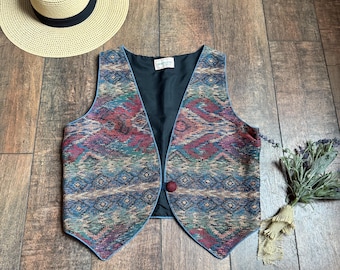 May include: A colourful, patterned waistcoat with a black lining and a single button fastening. The waistcoat has a geometric design in shades of blue, red, green, and brown.