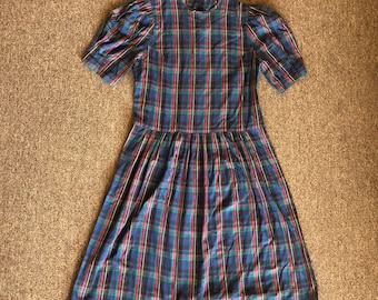 May include: A blue, green, red, and yellow plaid dress with a high neck and short sleeves. The dress has a gathered skirt and a fitted bodice.
