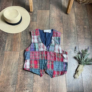 May include: A patchwork vest with a blue, red, and green plaid pattern. The vest has a button closure and is made of a soft, comfortable fabric.