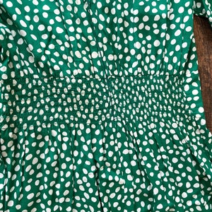 May include: Green dress with a white polka dot pattern. The dress has a fitted bodice and a gathered skirt. The dress has a zipper closure in the back.