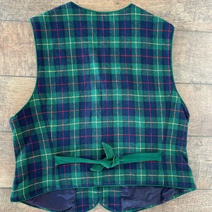 May include: A green, blue, red, and yellow plaid vest with a green velvet tie. The vest has a scalloped bottom and a dark blue lining.