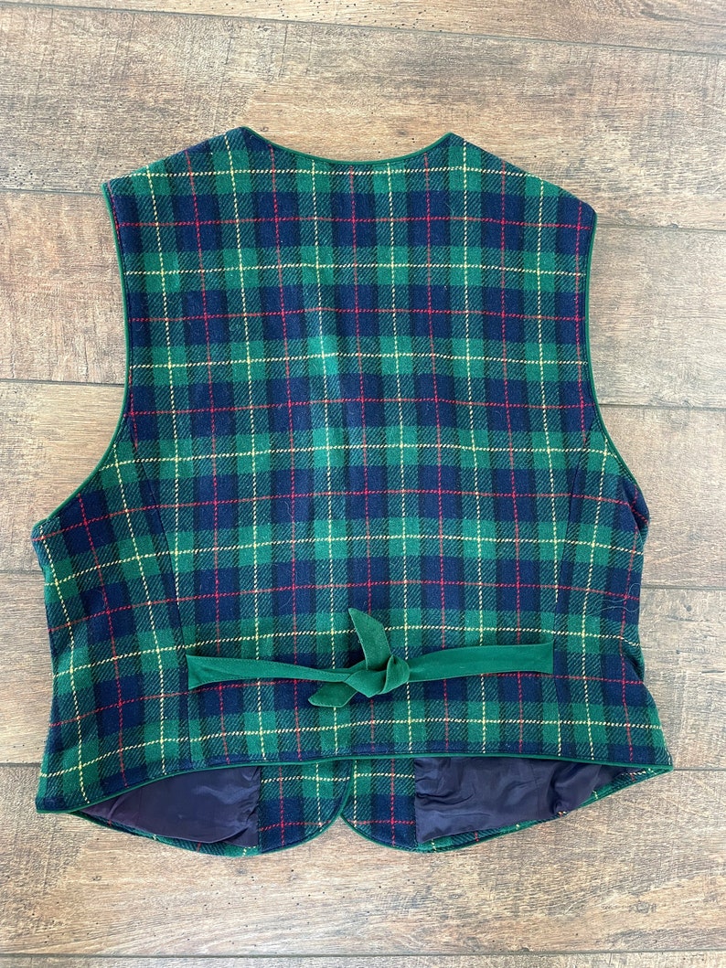 May include: A green, blue, red, and yellow plaid vest with a green velvet tie. The vest has a scalloped bottom and a dark blue lining.