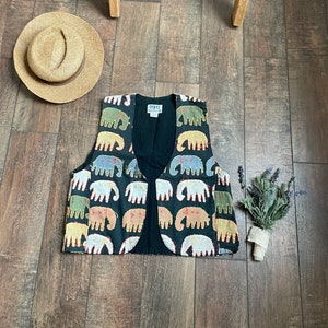 May include: A black vest with a colourful elephant print. The vest has a V-neck and is made of a soft, lightweight fabric.