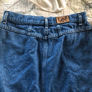 May include: A pair of blue denim jeans with a brown leather Lee label on the back waistband.