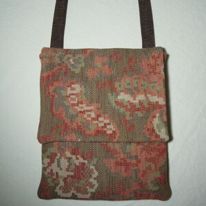 May include: A small, brown and green floral patterned bag with a brown strap. The bag is made of a woven fabric and has a flap closure.