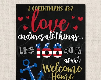 May include: A black chalkboard sign with the text "1 Corinthians 13:7 love endures all things... Like 168 days apart Welcome Home HMC MARIS". The sign features a red, white, and blue American flag design, a blue anchor, and gold hearts.