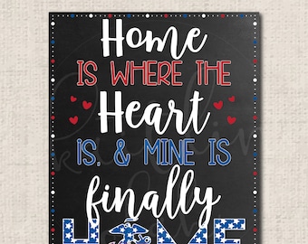 May include: Black rectangular sign with the text "Home is where the heart is & mine is finally HOME" in white, red, and blue. The word "HOME" is designed with the American flag. Small red hearts are scattered around the text.