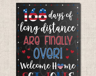 May include: A black chalkboard sign with white polka dots around the border. The sign says "168 days of long distance are finally over! Welcome home SGT. JONES". The numbers 168 are in red, white, and blue, and the rest of the text is in white. There are red and blue hearts around the text.