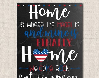 May include: A black chalkboard sign with white text that reads "Home is where the heart is and mine is finally home."  A red, white, and blue heart with stars is in the middle of the word "home".  The text "Welcome Back" is below the heart and the text "Sgt Simpson" is below that.