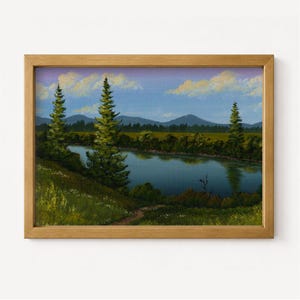 Pode incluir: Uma pintura de paisagem emoldurada apresentando um lago azul calmo cercado por pinheiros verdes e colinas gramadas. Ao fundo, montanhas azuis suaves situam-se sob um céu com nuvens leves. A moldura é feita de madeira castanha clara com acabamento.