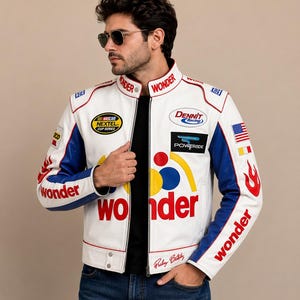 Könnte beinhalten: Eine weiße Rennjacke mit blauen Ärmeln, verziert mit rotem 'wonder'-Schriftzug, verschiedenen Sponsoren-Aufnähern wie NASCAR Nextel Cup Series, Dennit Racing und Powerade, einer kleinen amerikanischen Flagge und roten Flammenmotiven an den Ärmeln.