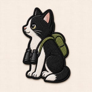 May include: An embroidered patch featuring a black and white cat sitting in profile. The cat wears a green backpack and has black binoculars hanging around its neck. The cat has white fur on its chest, face, and tail tip, with pink inner ears.