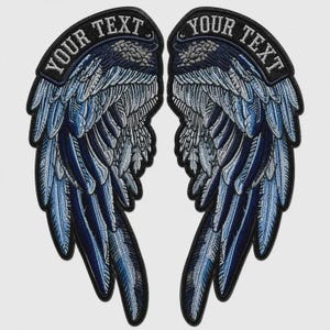 Puede incluir: Un par de parches bordados de alas en tonos azules, grises y negros. Cada ala tiene una banda negra curva en la parte superior con el texto blanco YOUR TEXT bordado en una fuente negrita y mayúscula sobre la superficie arqueada.