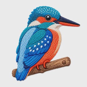 May include: An embroidered patch of a kingfisher bird perched on a brown branch. The bird features vibrant blue, turquoise, and orange threadwork with a long, dark beak and white accents on the head and neck, showcasing detailed stitching.