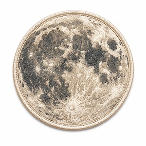 Könnte beinhalten: Ein kreisförmiger bestickter Aufnäher mit einem detaillierten Mondoberflächendesign. Der Mond ist in Creme-, Beige- und dunklen Anthrazittönen gehalten und zeigt Krater sowie texturiertes Gelände mit einem Rand aus hellbeigem Garn.