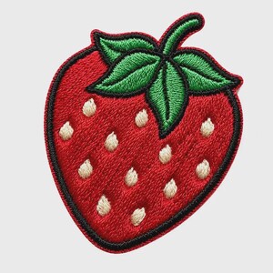 以下が含まれることがあります： イチゴの形をした刺繍ワッペン。果実は鮮やかな赤色で、黒いステッチの縁取りが施されており、表面には小さなオフホワイトの種のようなディテールがあります。上部には、鮮やかな緑色の刺繍が施された3枚の葉が付いています。