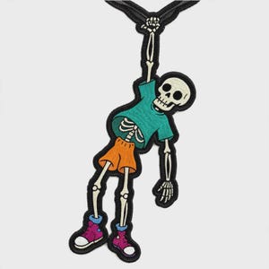 May include: An embroidered patch featuring a skeleton hanging by one hand. The skeleton wears a teal t-shirt, orange shorts, and pink high-top sneakers. The design is outlined in black thread, with the skeleton figure rendered in off-white.