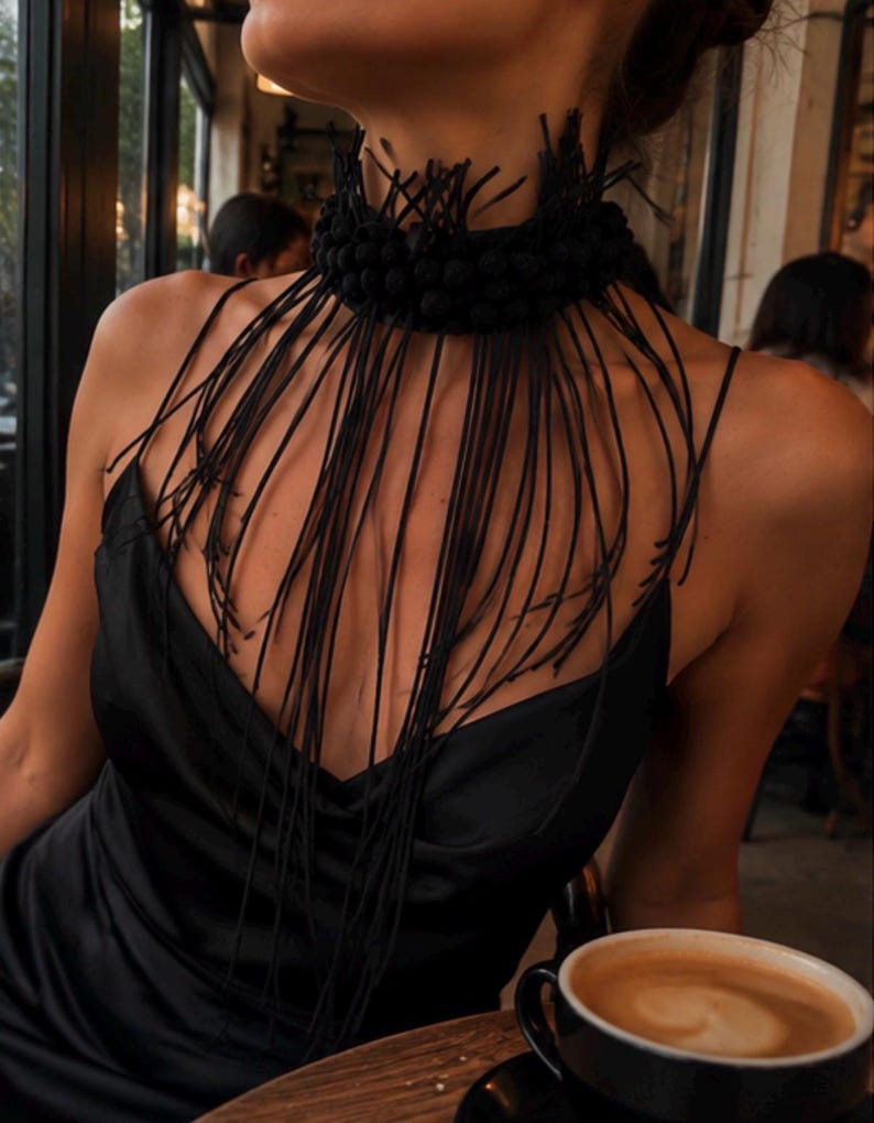 May include: A black choker necklace featuring a textured, beaded collar base with long, thin, dangling black fringe strands that drape over the chest, paired with a black satin slip dress with thin spaghetti straps and a V-neckline.