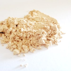 May include: A close-up of a pile of light beige powder. The powder is finely ground and has a smooth texture.