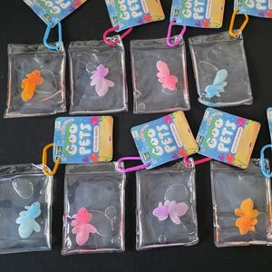 May include: A collection of Goo Pets Goldfish Series keychains, each featuring a small, colorful, translucent silicone goldfish toy sealed inside a clear, liquid-filled plastic pouch with a plastic carabiner clip attached to the top.