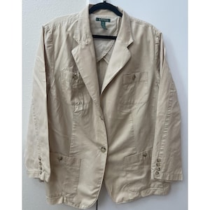 May include: A beige long-sleeve blazer featuring a notched lapel, a single-button front closure, and four front pockets with button flaps. The interior label reads Lauren Ralph Lauren. The sleeves have four buttons at each cuff.