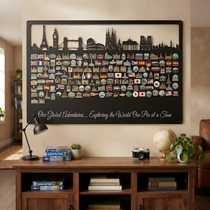 May include: A large rectangular black metal wall display board featuring a laser-cut skyline silhouette at the top and numerous colorful travel-themed enamel pins attached to the surface. The text "Our Global Adventures... Exploring the World One Pin at a Time" is printed in white script at the bottom.