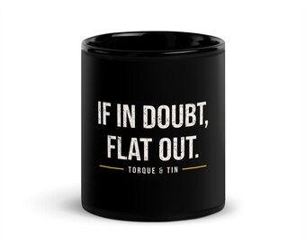 May include: A black ceramic mug featuring the white distressed text IF IN DOUBT, FLAT OUT. Below the text is a thin yellow horizontal line and the words TORQUE & TIN in white. The mug has a smooth finish and a cylindrical shape.