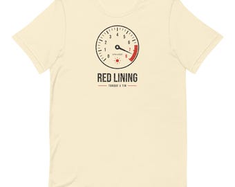 May include: A cream-colored short-sleeve t-shirt featuring a graphic of a tachometer gauge with a red zone. Below the gauge, the text reads RED LINING and TORQUE & TIN in a distressed black font, with a small red sun icon centered.